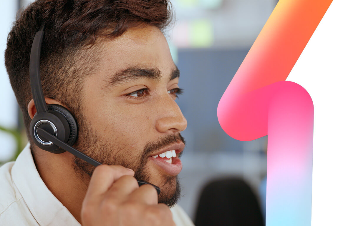 Asian male conact centre agent in office with headset on talking to a customer.