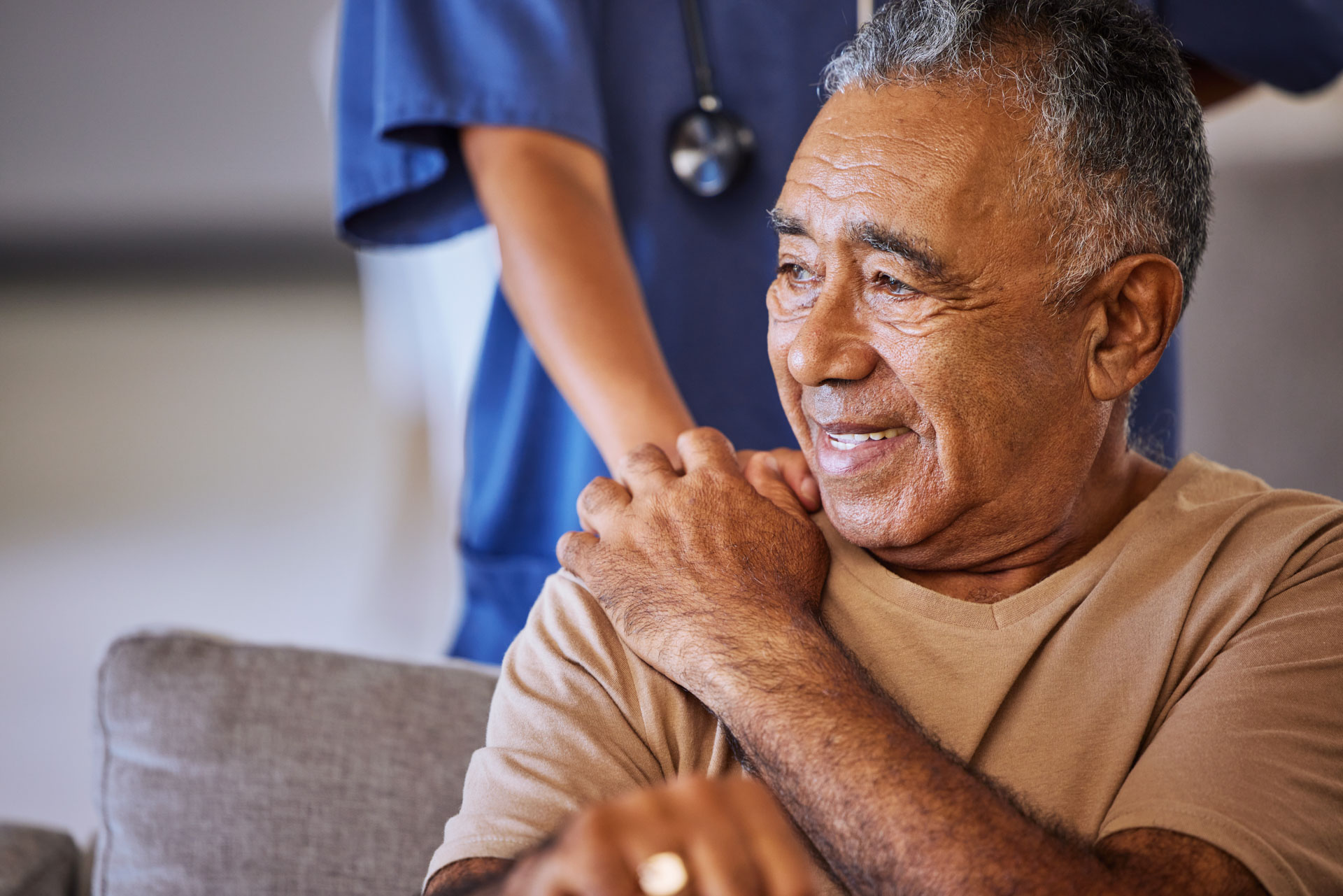 A male patient is comforted by a nurse with a hand on his shoulder