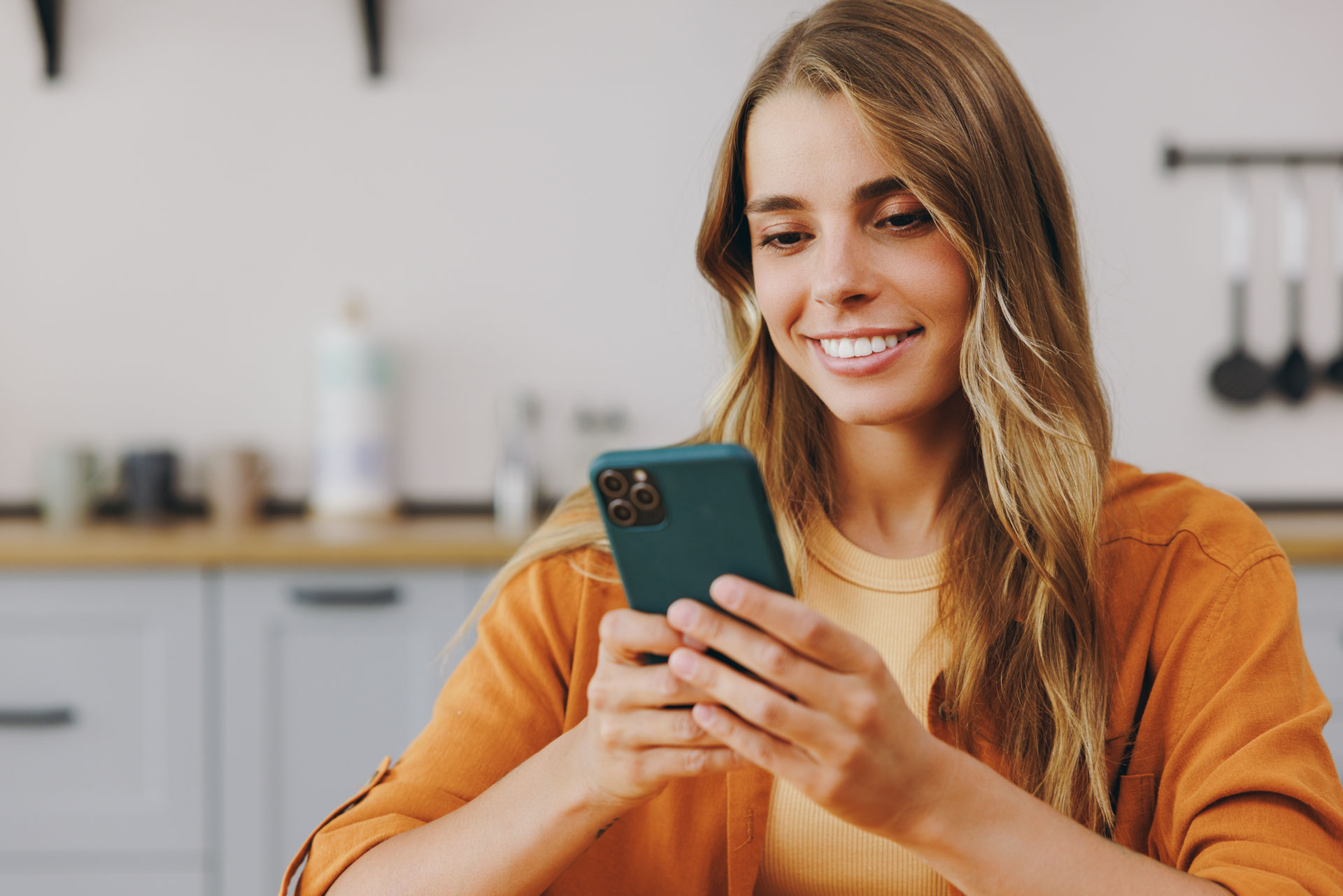 A happy young woman uses the HBS Platform at home on her smartphone