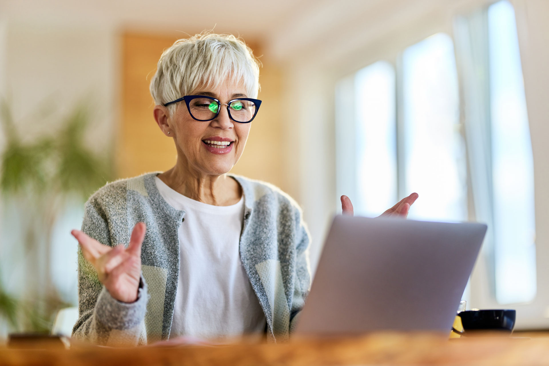 Happy mature woman having a video call over a computer at home.