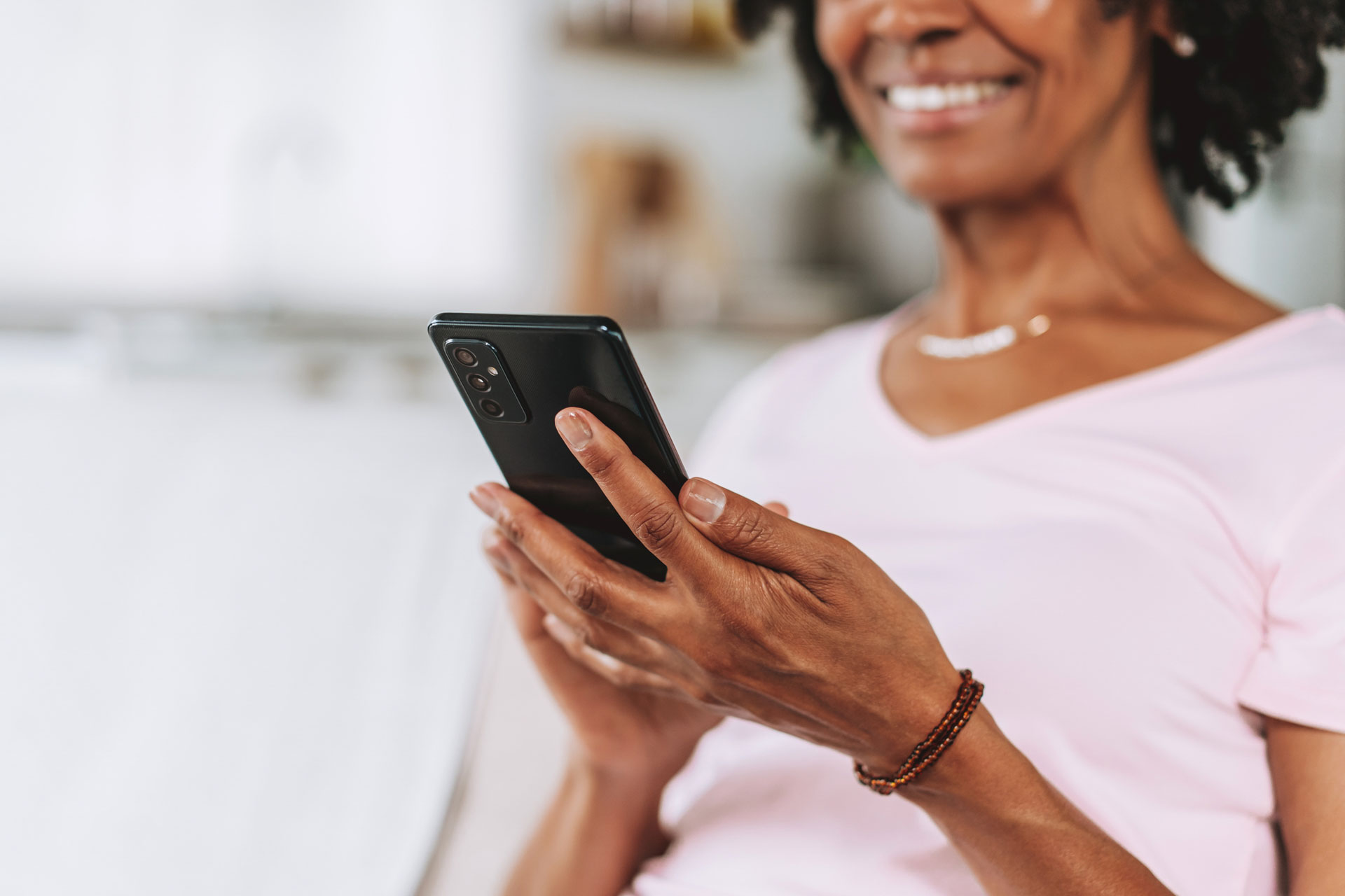 Close-up detail of a senior Black woman's hands holding and using a smartphone.