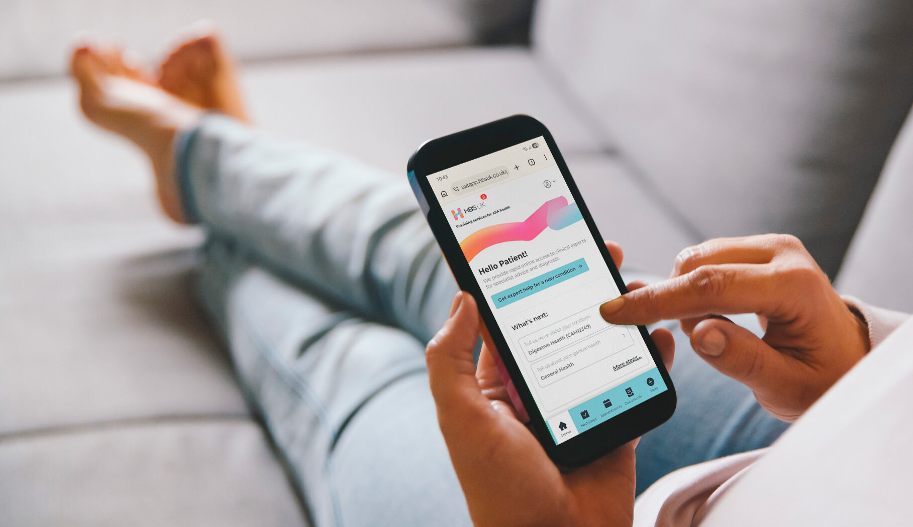 A woman uses the HBS Platform on her smartphone while relaxing on her sofa at home