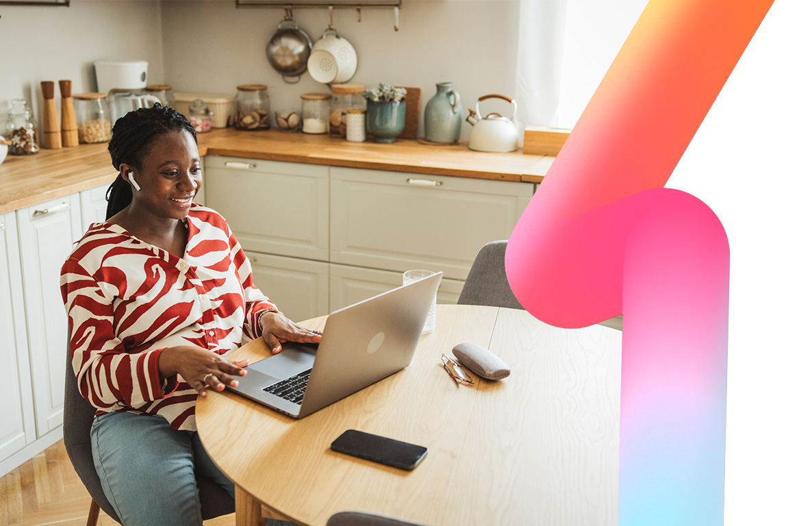 Young pregnant woman having a video call on her laptop on the kitchen table