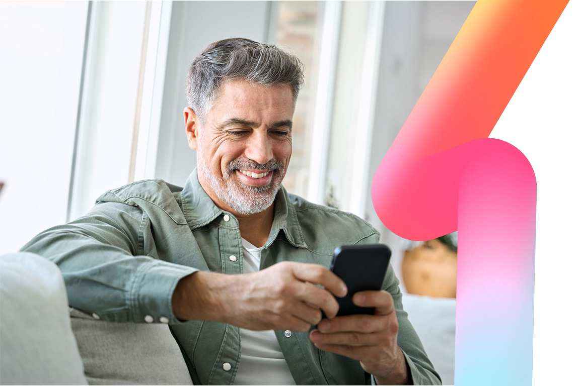 A man uses the HBS Platform on his phone at home, while sat on his sofa smiling