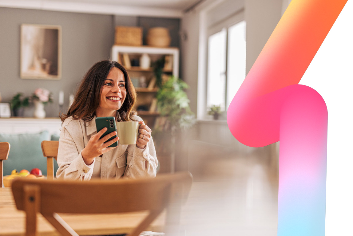 Smiling woman sitting at a dining table, enjoying a cup of coffee while using her smartphone